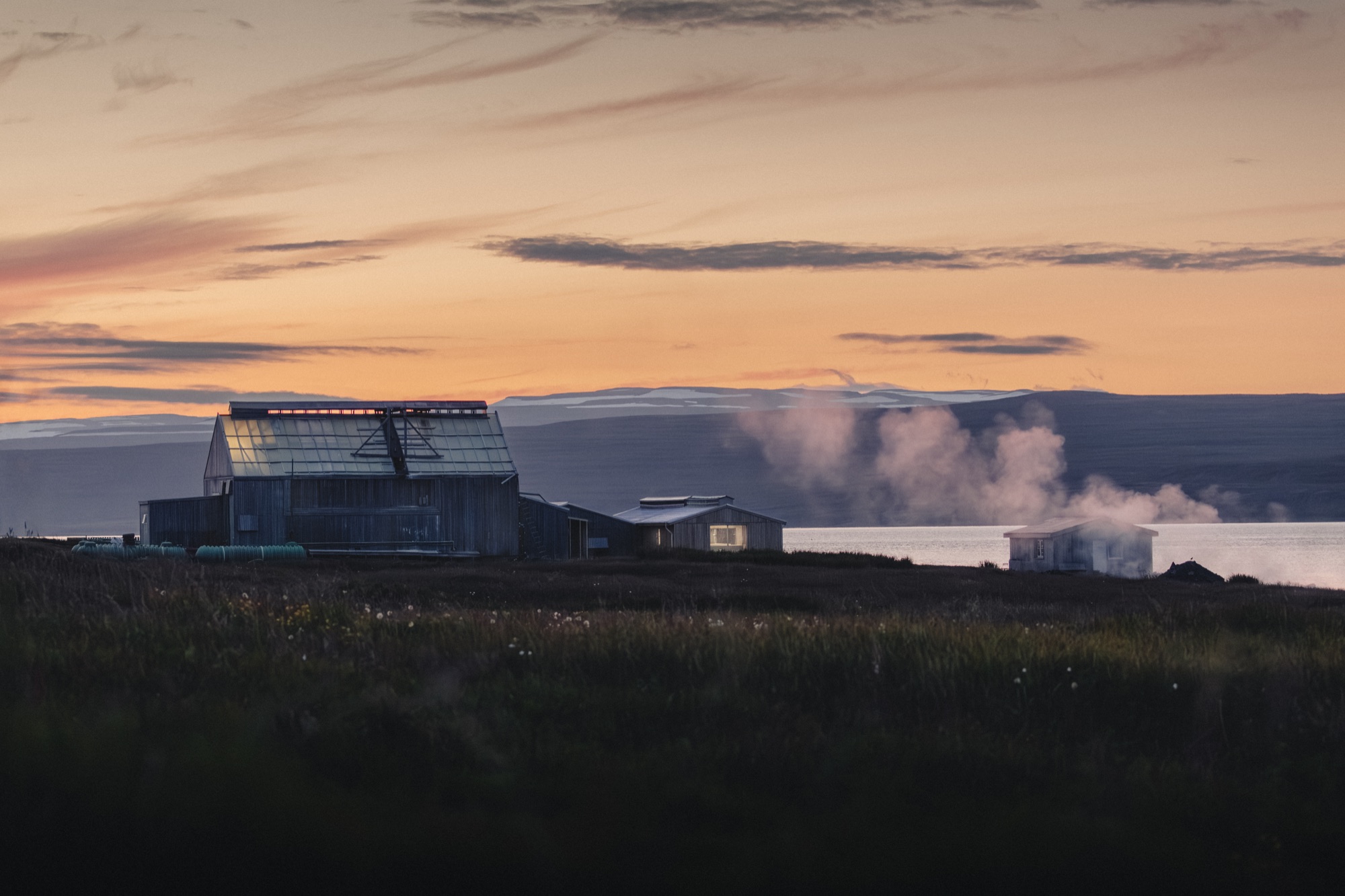 Saltverk buildings beside the water at sunset with steam rising nearby
